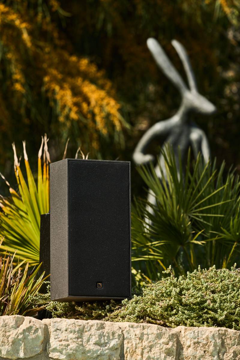 Loa ngoài trời L-Acoustics tinh tế ẩn mình trong cảnh quan cây xanh.